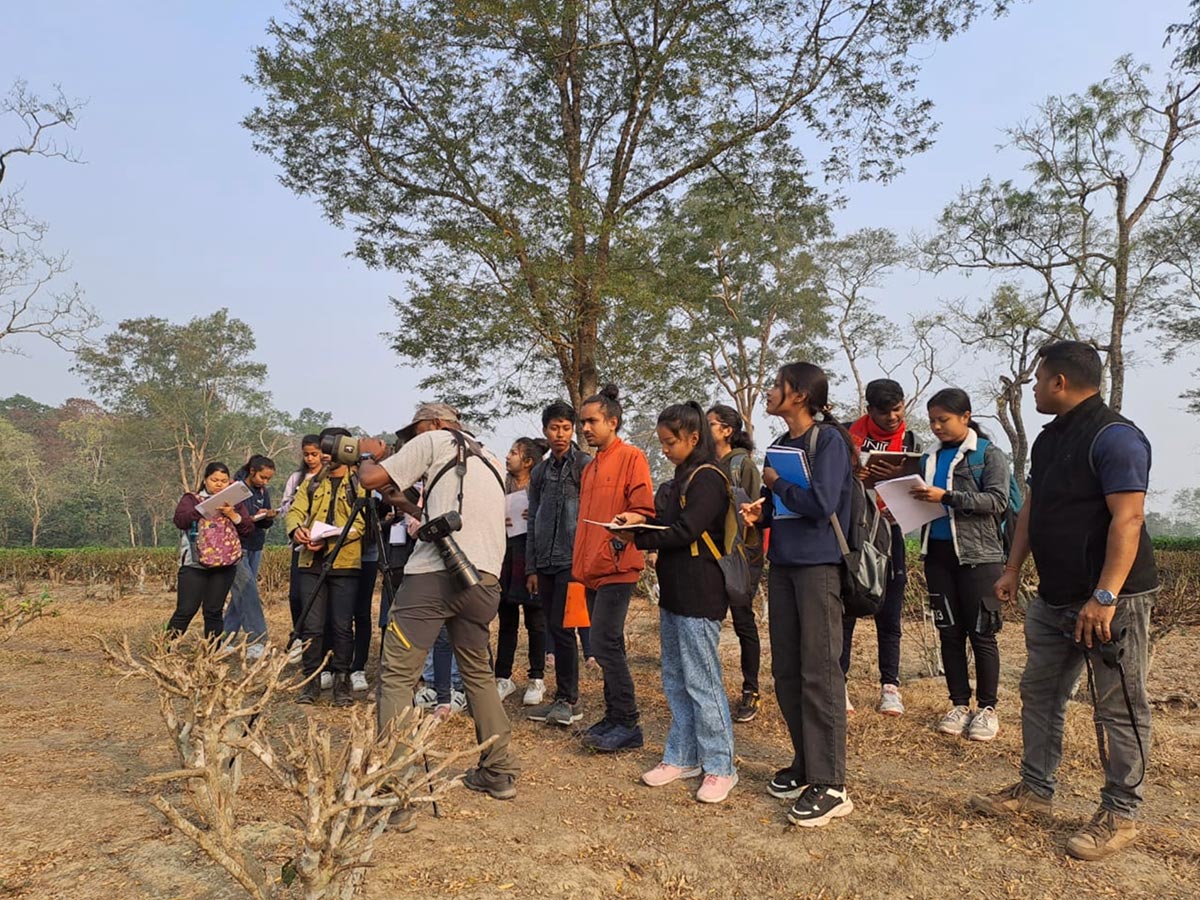 A group of people standing outside taking notes and looking through a scope