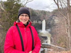 Female staff member Josee Rousseau stands in front of a big waterfall on a cold day.