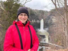 Female staff member Josee Rousseau stands in front of a big waterfall on a cold day.