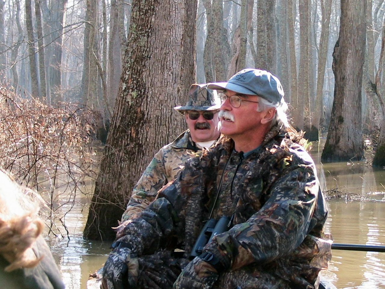 John Fitzpatrick wearing camo, sitting in canoe in swamp