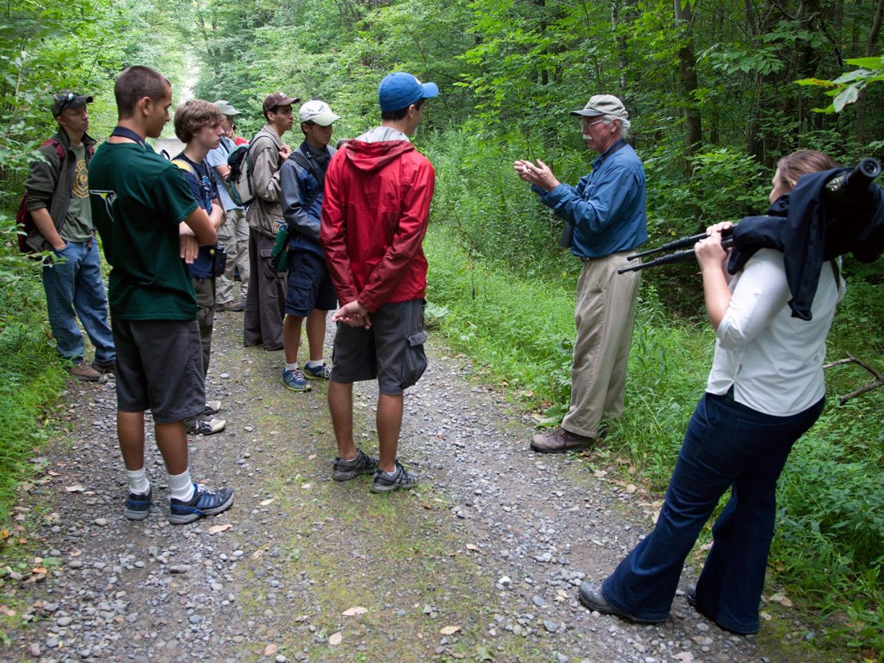 John Fitzpatrick speaks to a group of young birdwatchers on a forested road
