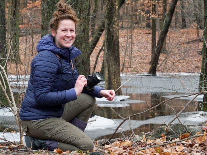 Jess Ahearn sits in a forest while birdwatching.