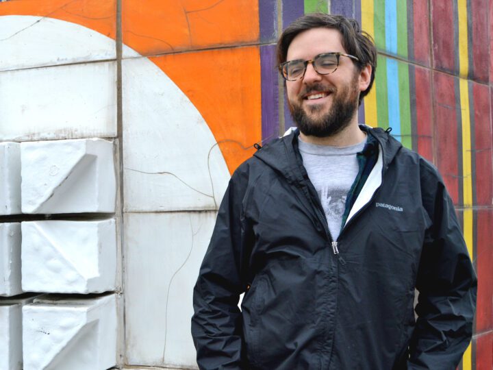 Bearded man stands in front of a painted wall.