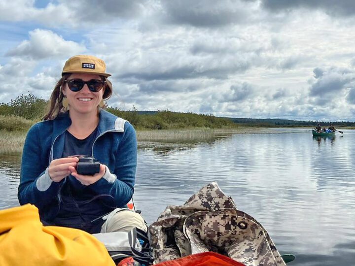 A girl with sunglasses sits in a boat.