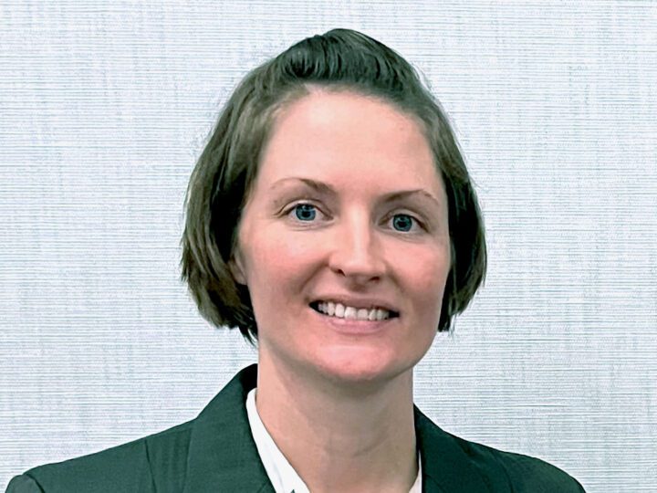 Smiling woman in suit faces the camera.