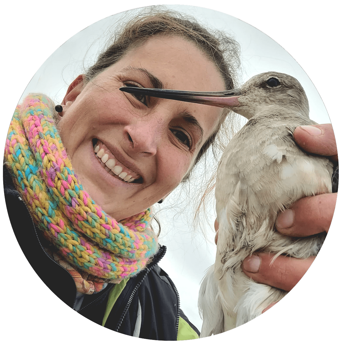 Woman with a multicolored scarf holds a grey bird with a long bill.