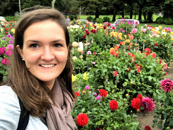 Woman smiles at the camera with a background full of potted flowers.