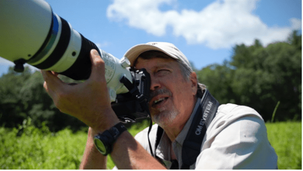 Man lifting a camera to photograph a bird