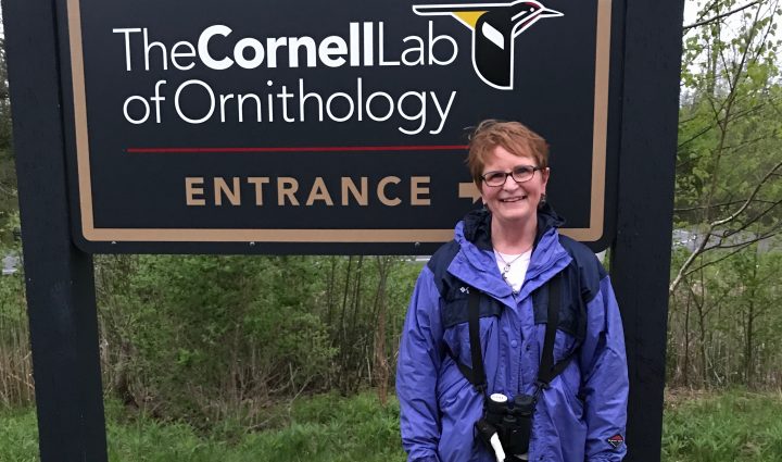 Barbara Jacobs-Smith in front of the Cornell Lab of Ornithology Entrance sign