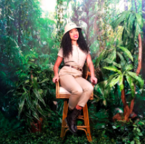 Picture of Jamaka Fisher sitting in front of jungle-like plants