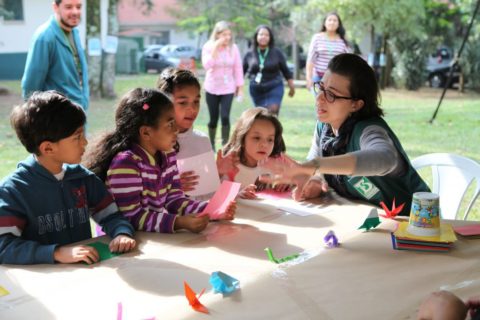 A woman explaining how to do origami to kids