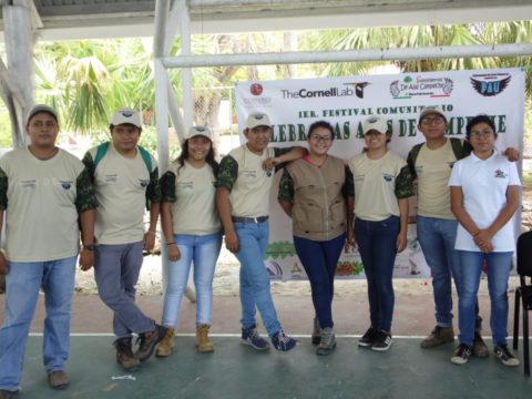 Youth posing in front of a banner showcasing the first festival of birds in Campeche, Mexico