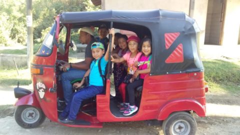 A group of students in a red tuk tuk