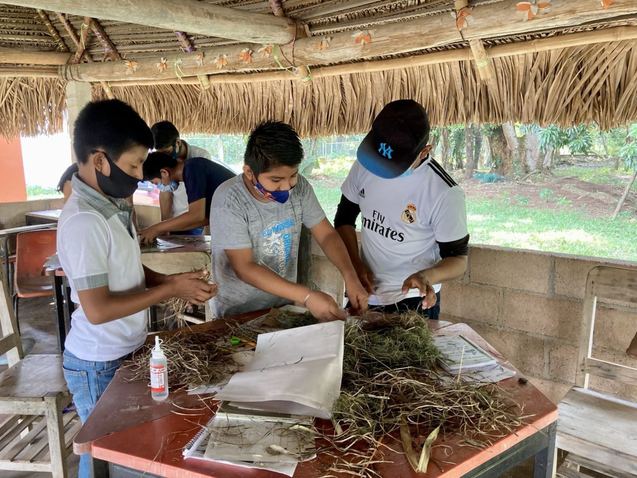 Three boys building a nest with grass