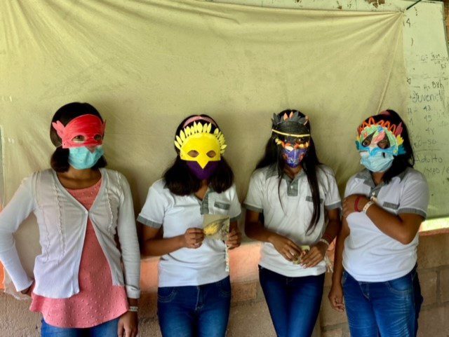 Four girls wearing colorful paper masks