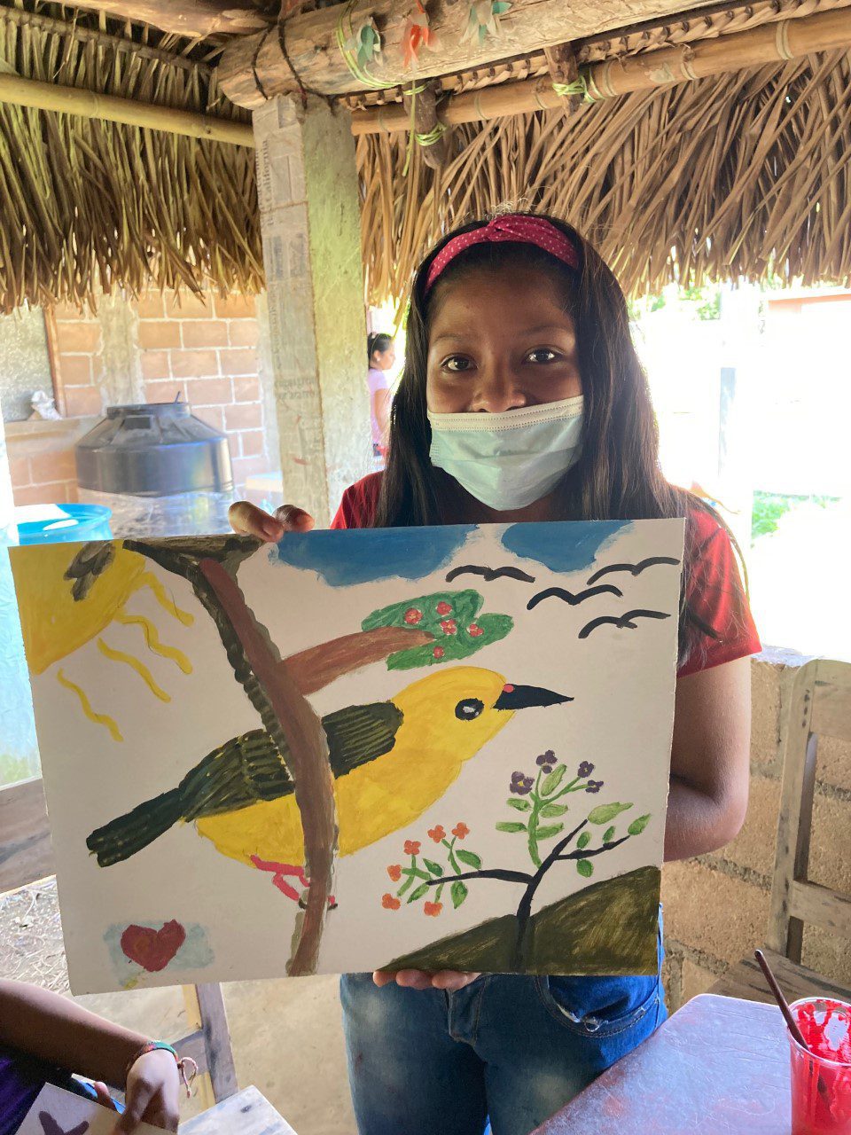 Young girl with a facemask holding a painting of a yellow bird