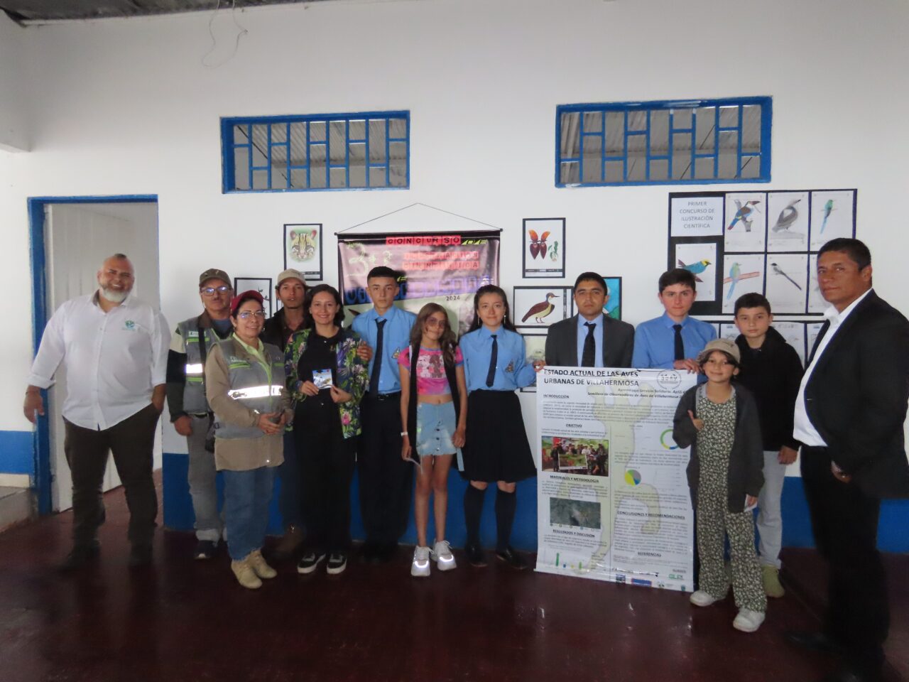 Multiple students and instructors are facing the camera. They are holding a poster titled "Current state of the urban birds of Villahermosa."