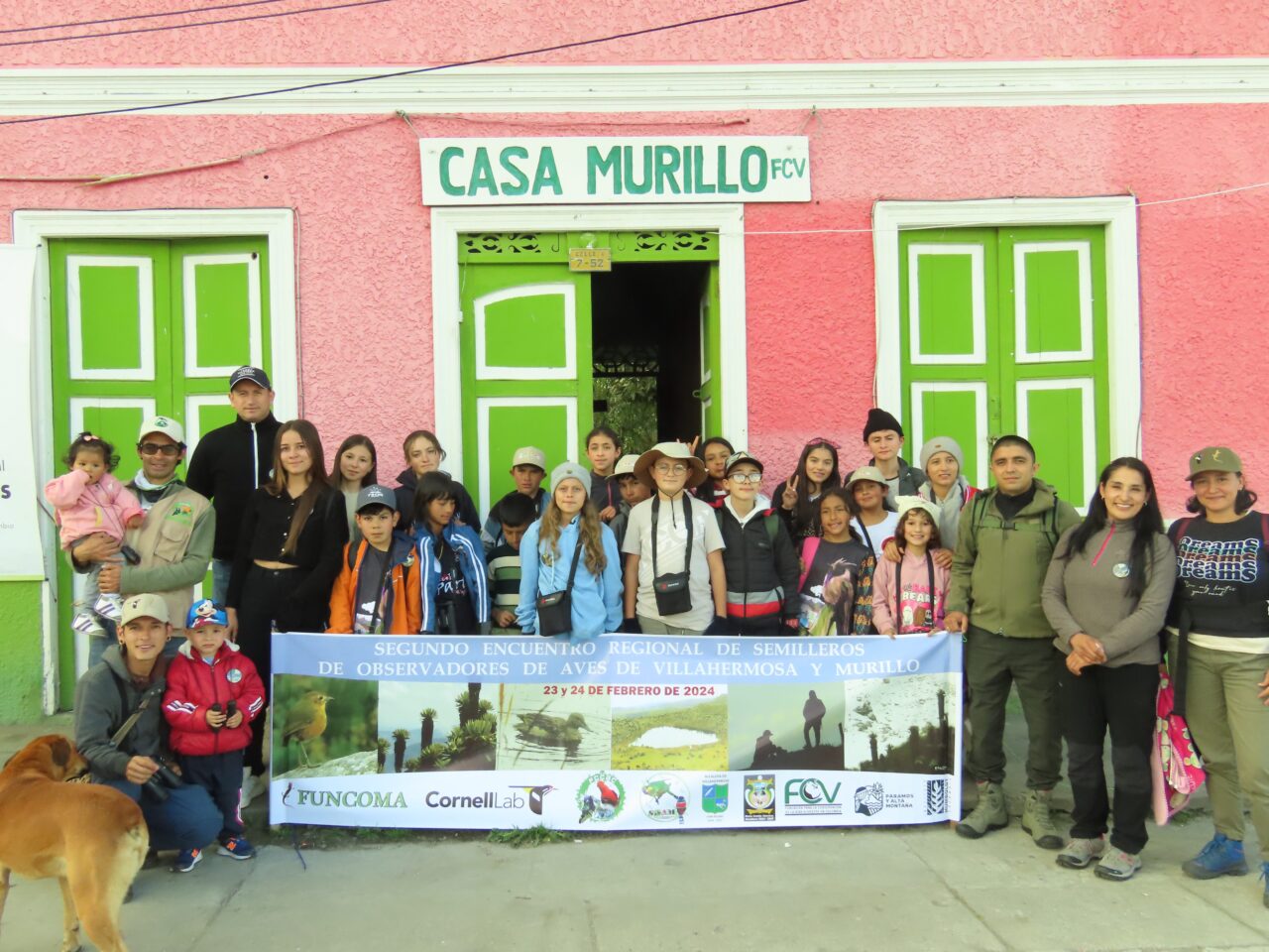 There is a group of students and instructors posing with a banner in front of "Casa Murillo."