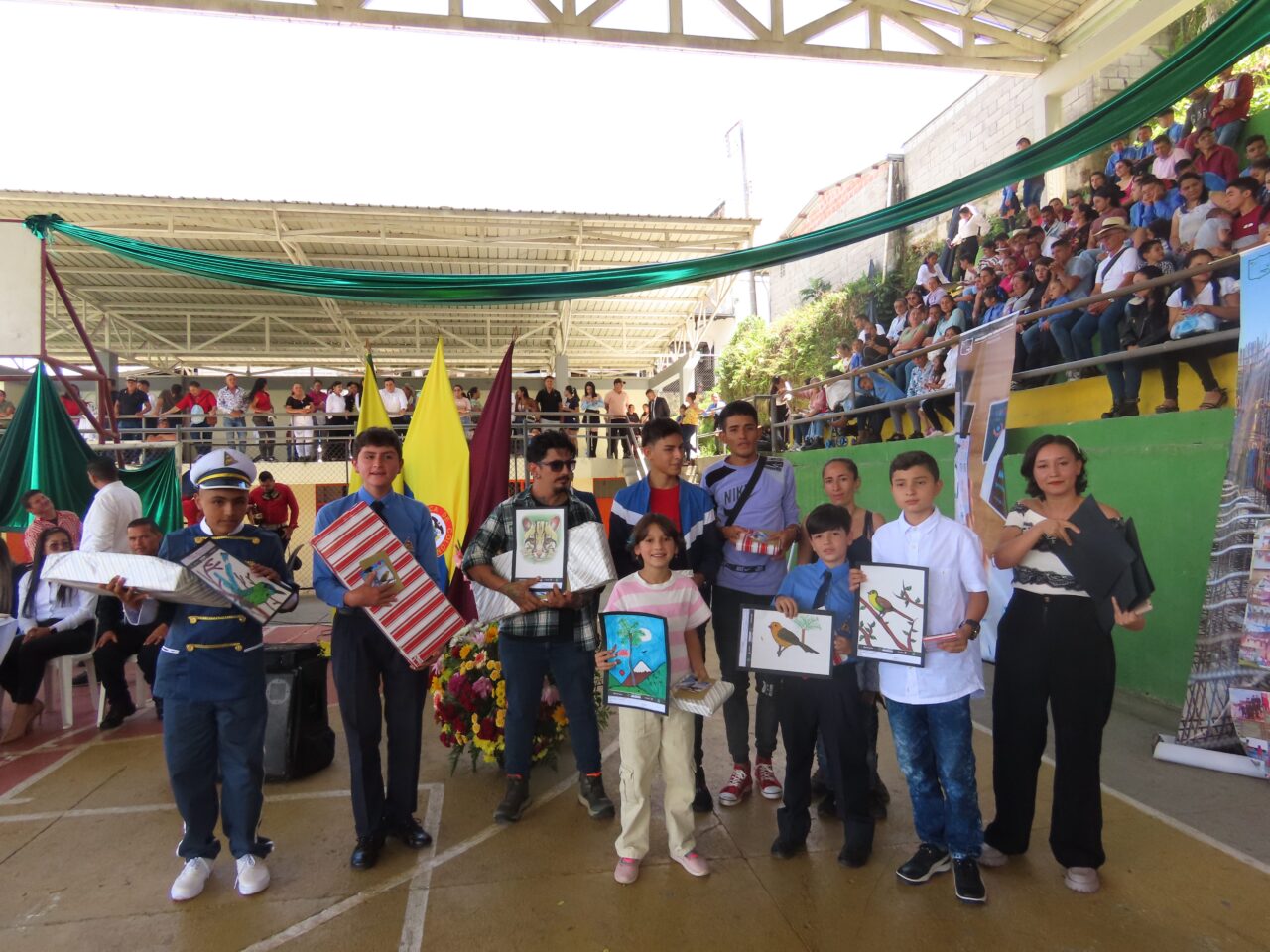 Ten people are facing the camera. They are proudly showcasing their colorful artwork.
